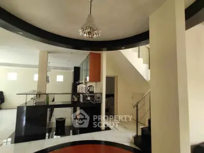 Modern open-plan kitchen with sleek design and staircase in stylish home interior.
