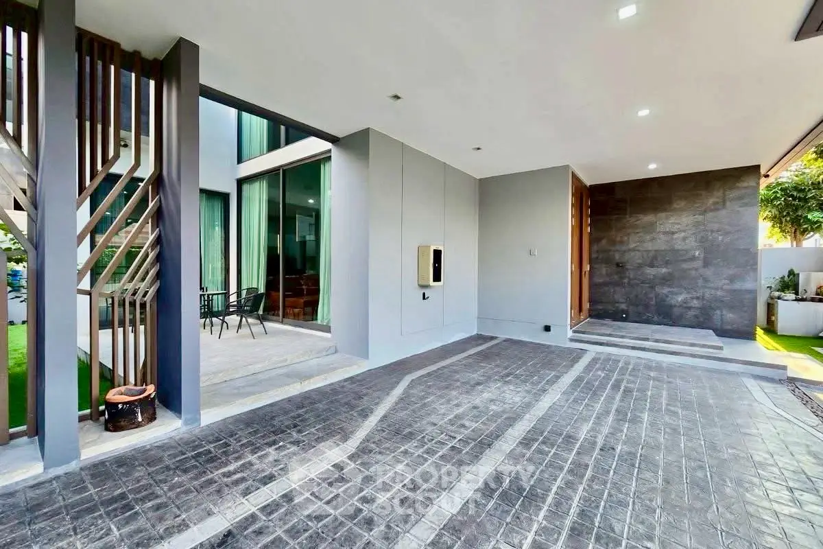 Modern luxury home entrance with spacious driveway and sleek architectural design.