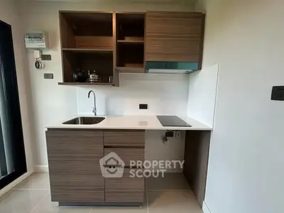 Modern compact kitchen with sleek wooden cabinets and built-in appliances in a stylish apartment.