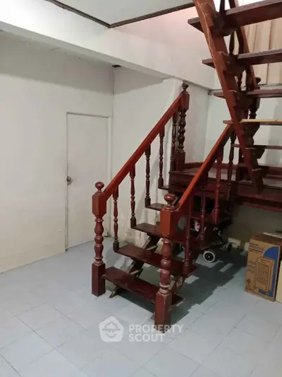 Charming wooden staircase in cozy interior space with tiled flooring, perfect for a warm home ambiance.