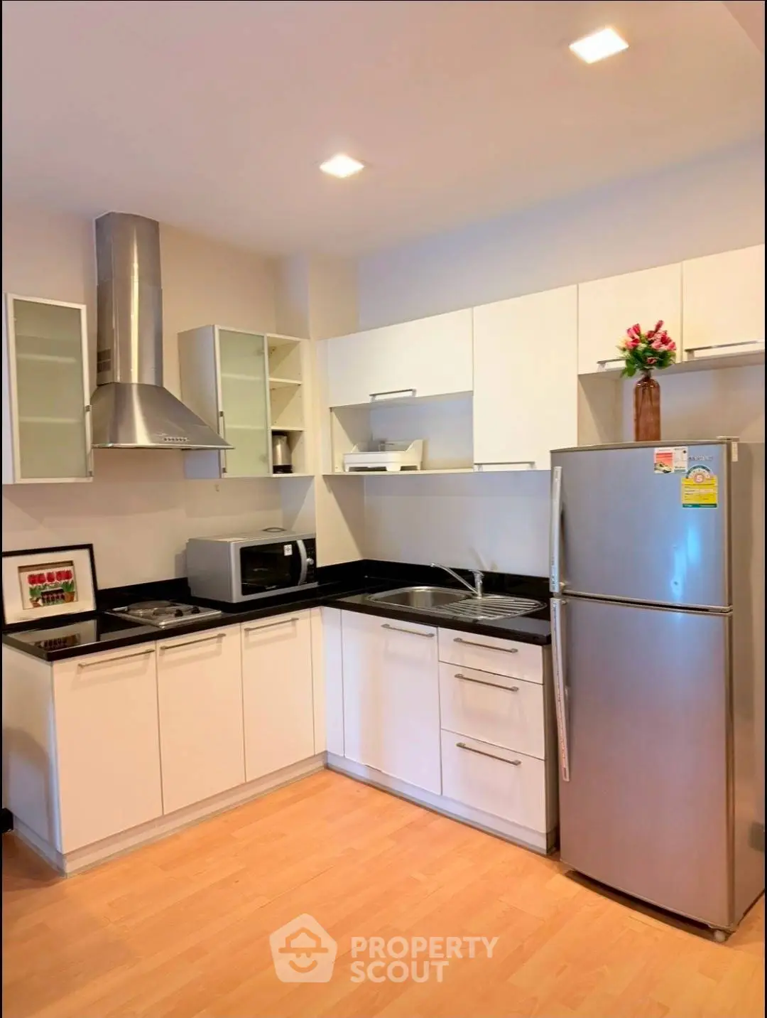 Modern kitchen with sleek white cabinets and stainless steel appliances in a cozy apartment.