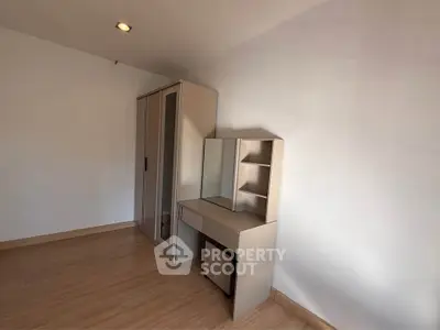 Minimalist bedroom with wardrobe and vanity set, featuring sleek design and ample storage space.
