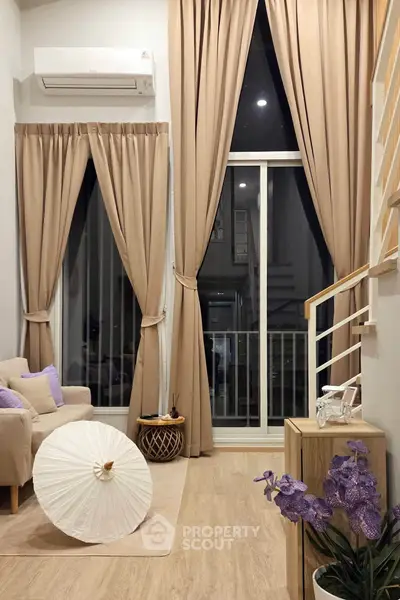 Elegant living room with high ceilings, large windows, and stylish decor in a modern apartment.