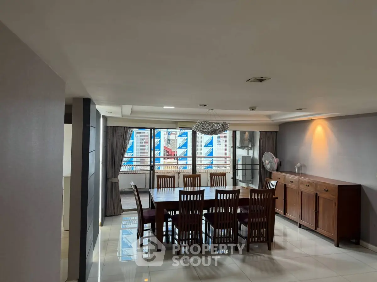 Spacious dining area with elegant wooden furniture and large windows offering city views.