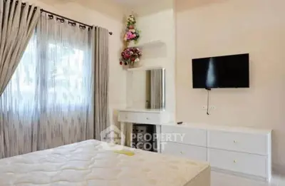 Bright bedroom with elegant decor, featuring a wall-mounted TV and stylish curtains.
