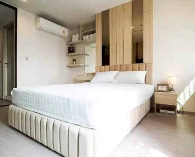 Modern bedroom with stylish decor and natural light, featuring a comfortable bed and elegant shelving.