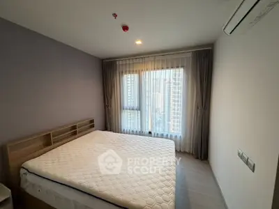 Modern bedroom with large window and city view, featuring a comfortable bed and air conditioning.