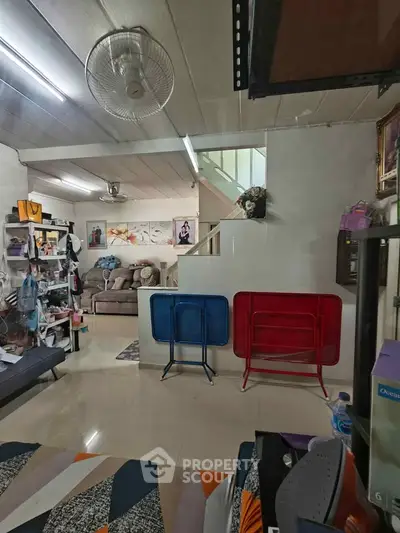 Cozy living room with modern decor and staircase, featuring stylish furniture and vibrant wall art.