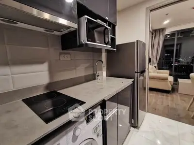 Modern kitchen with sleek appliances and open layout leading to cozy living room.
