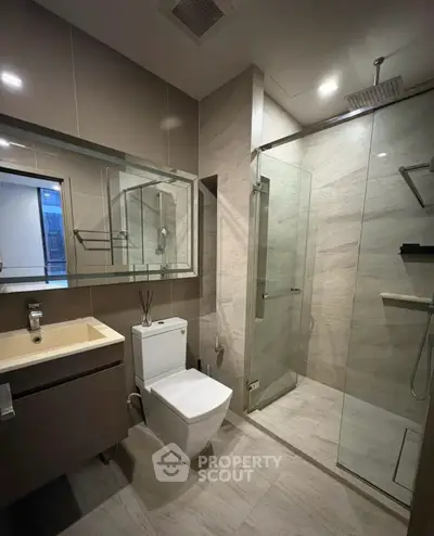 Modern bathroom with glass shower and sleek fixtures in luxury apartment.