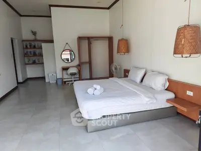 Spacious bedroom with modern decor and natural lighting, featuring a comfortable bed and stylish furnishings.