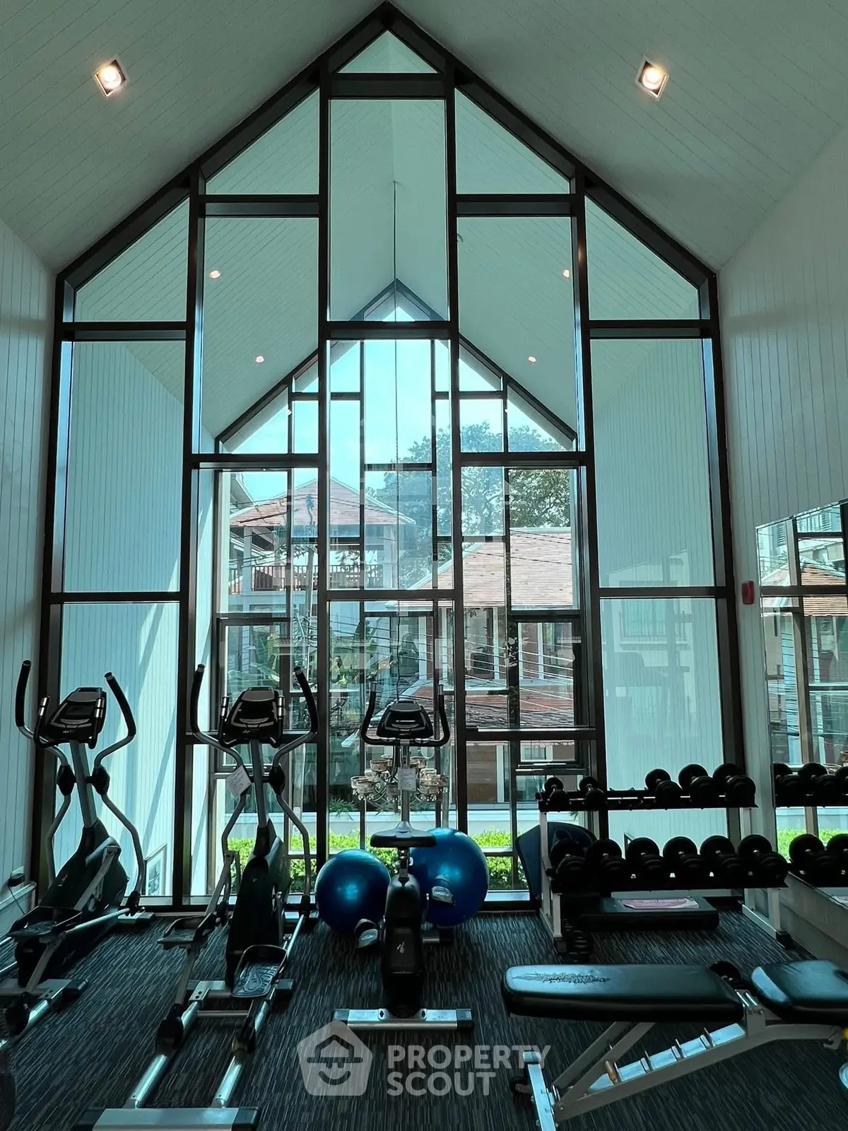Stunning gym with floor-to-ceiling windows and modern equipment in luxury residential complex.