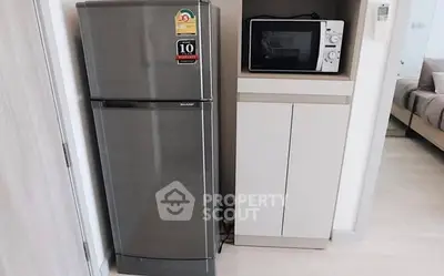 Modern kitchen with stainless steel fridge and microwave in compact space.