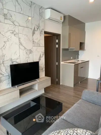 Modern living room with marble accent wall and sleek kitchen in open layout apartment.