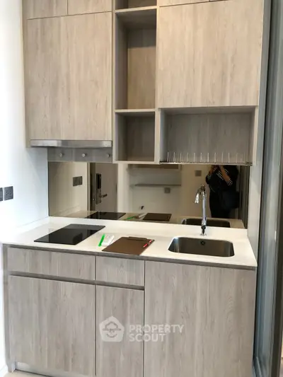 Modern compact kitchen with sleek cabinetry and built-in appliances in a stylish apartment.