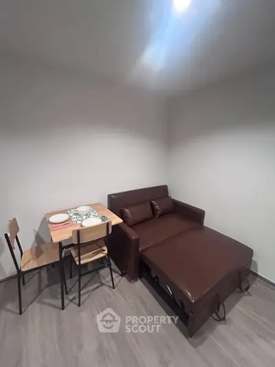 Cozy living room with brown sofa bed and dining table, perfect for compact spaces.