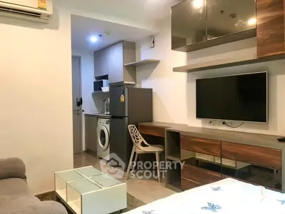 Modern studio apartment with compact kitchen and living area, featuring a washing machine and sleek furniture.