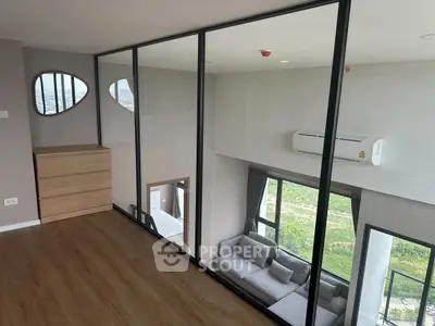 Modern living room with glass partition and scenic view, featuring stylish furniture and wooden flooring.