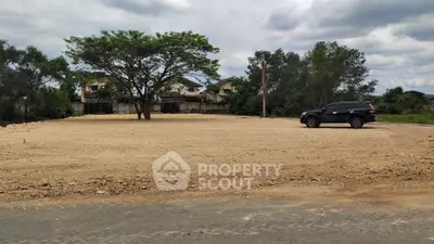 Spacious vacant land with potential for development, surrounded by greenery and residential homes.