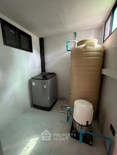 Utility room with water tank and washing machine in modern home