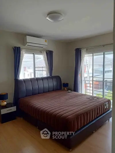 Spacious bedroom with large windows and modern furnishings in a stylish home.