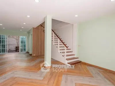 Spacious modern living room with stylish wooden flooring and staircase, perfect for family gatherings.