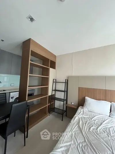 Modern studio apartment with sleek kitchen and cozy bedroom area, featuring stylish shelving and contemporary design.