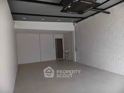 Spacious modern interior with tiled flooring and exposed brick wall, ideal for versatile use.