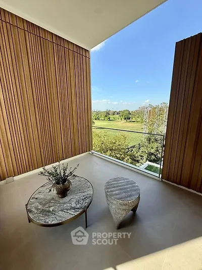 Spacious balcony with elegant furniture and stunning green view, perfect for relaxation and outdoor enjoyment.
