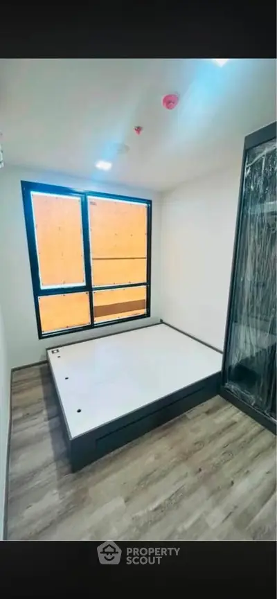 Modern bedroom with large window and sleek flooring in a contemporary apartment.