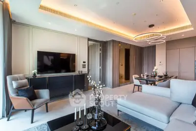 Luxurious modern living room with elegant decor and open dining area, featuring stylish lighting and a sleek TV setup.