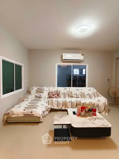 Spacious living room with modern decor and air conditioning, featuring a cozy sectional sofa and sleek coffee table.