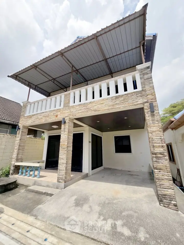 Charming two-story house with stone facade and spacious balcony, perfect for family living.