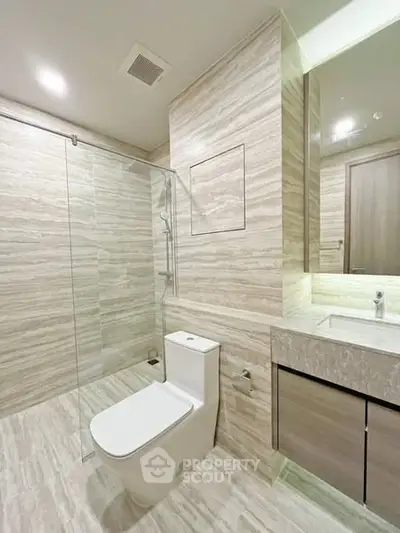 Modern bathroom with glass shower and sleek fixtures in luxury apartment.