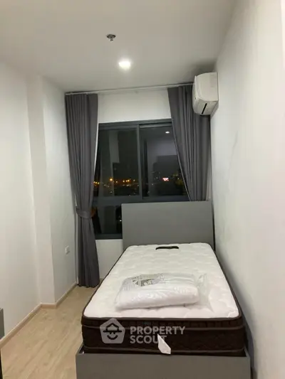 Cozy bedroom with modern decor and city view, featuring a comfortable bed and air conditioning.