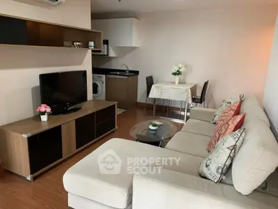 Cozy living room with modern furniture and compact kitchen in open layout apartment.