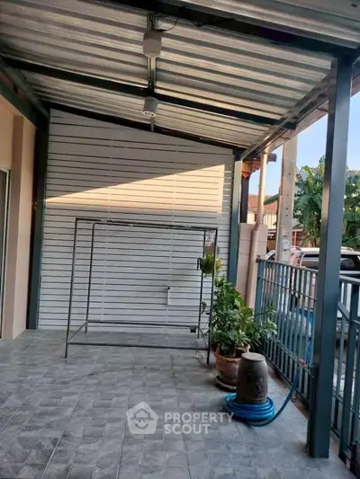 Spacious covered patio with tiled flooring and garden view, perfect for outdoor relaxation.