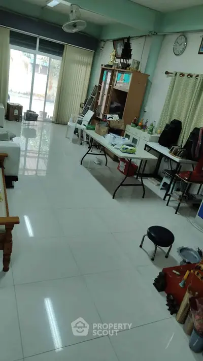 Spacious living room with tiled floor and large window, ideal for family gatherings.