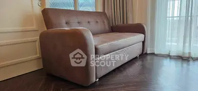 Elegant brown sofa in a stylish living room with large windows and wooden flooring.