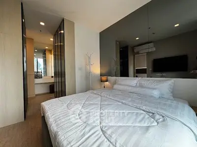 Modern bedroom with stylish decor and large mirror, featuring a cozy bed and sleek design.