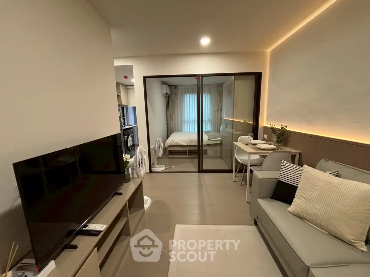 Modern living room with sleek furniture and sliding glass doors leading to a cozy bedroom.
