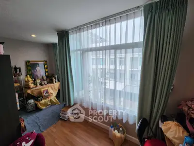 Cozy bedroom with large window and wooden flooring, perfect for natural light lovers.