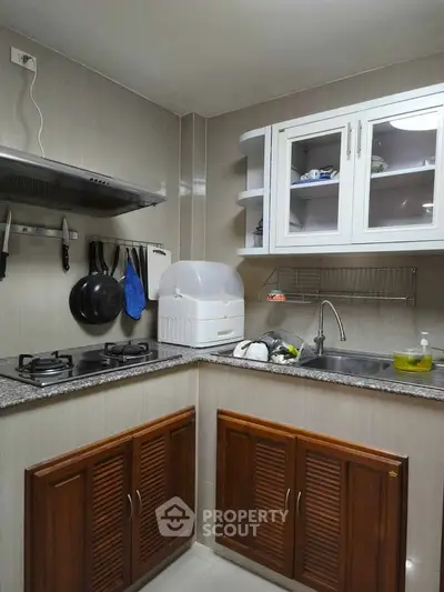 Charming kitchen with closed layout and gas stove, featuring modern cabinetry and sleek countertops.