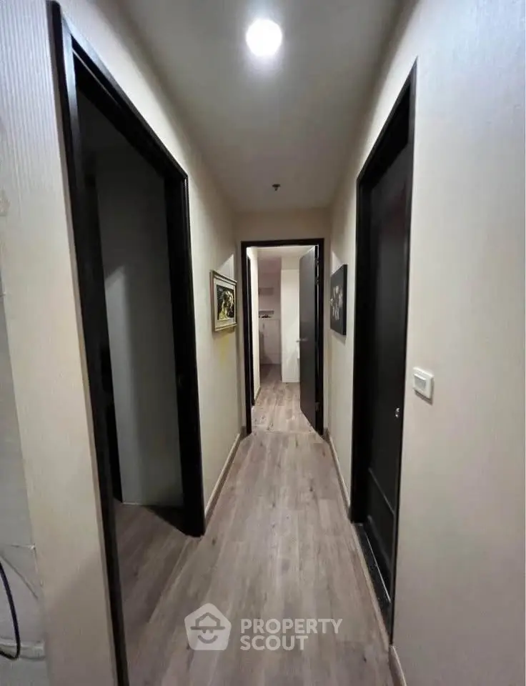 Modern apartment hallway with wooden flooring and recessed lighting