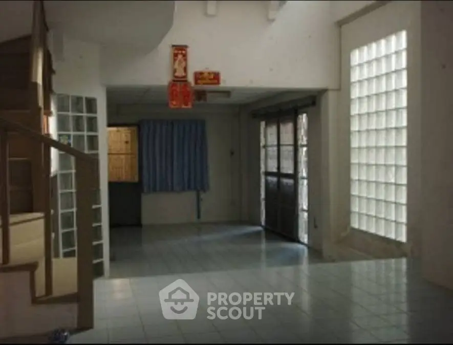 Spacious interior with tiled flooring and glass block wall, ideal for creative renovation.