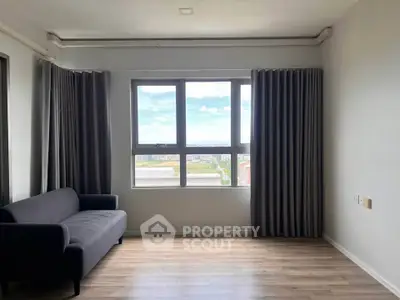 Spacious living room with large window offering a stunning view, featuring modern gray sofa and elegant curtains.