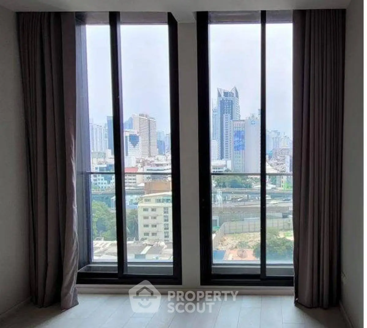 Stunning city view from modern apartment window with floor-to-ceiling glass.