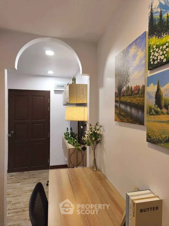 Charming study nook with wooden desk, elegant decor, and warm lighting in a cozy apartment.