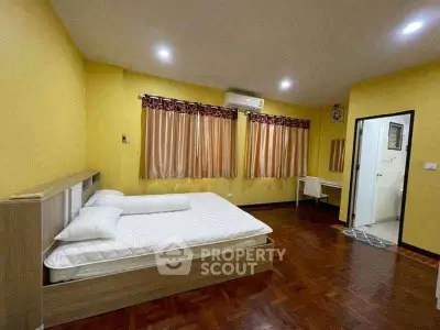 Spacious bedroom with wooden flooring and ensuite bathroom in modern apartment.