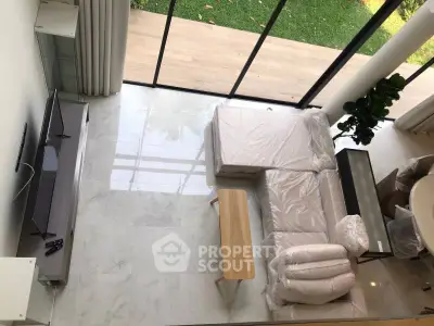 Spacious modern living room with large windows and garden view, featuring sleek furniture and elegant marble flooring.